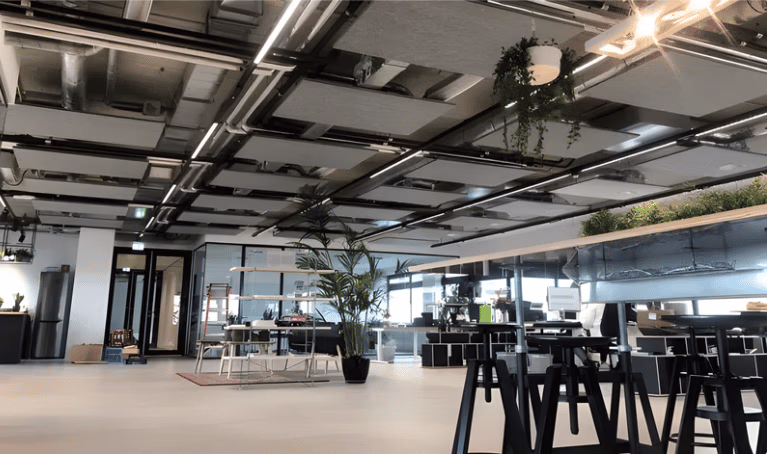 PET-vilt plafondeilanden boven werkzones in een open kantoor, ter ondersteuning van indeling in verschillende werkzones.
